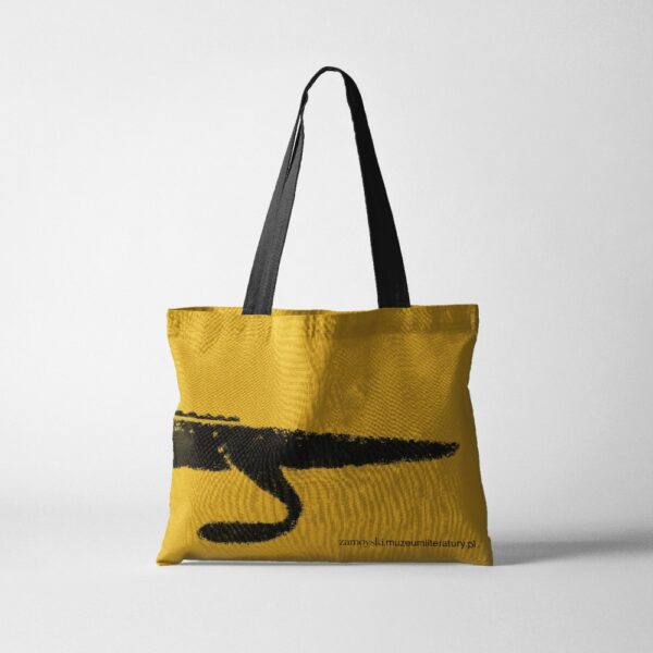 Żółta, płócienna torba. W centralnej części umieszczony nadruk czarnego krokodyla - tułów z ogonem.